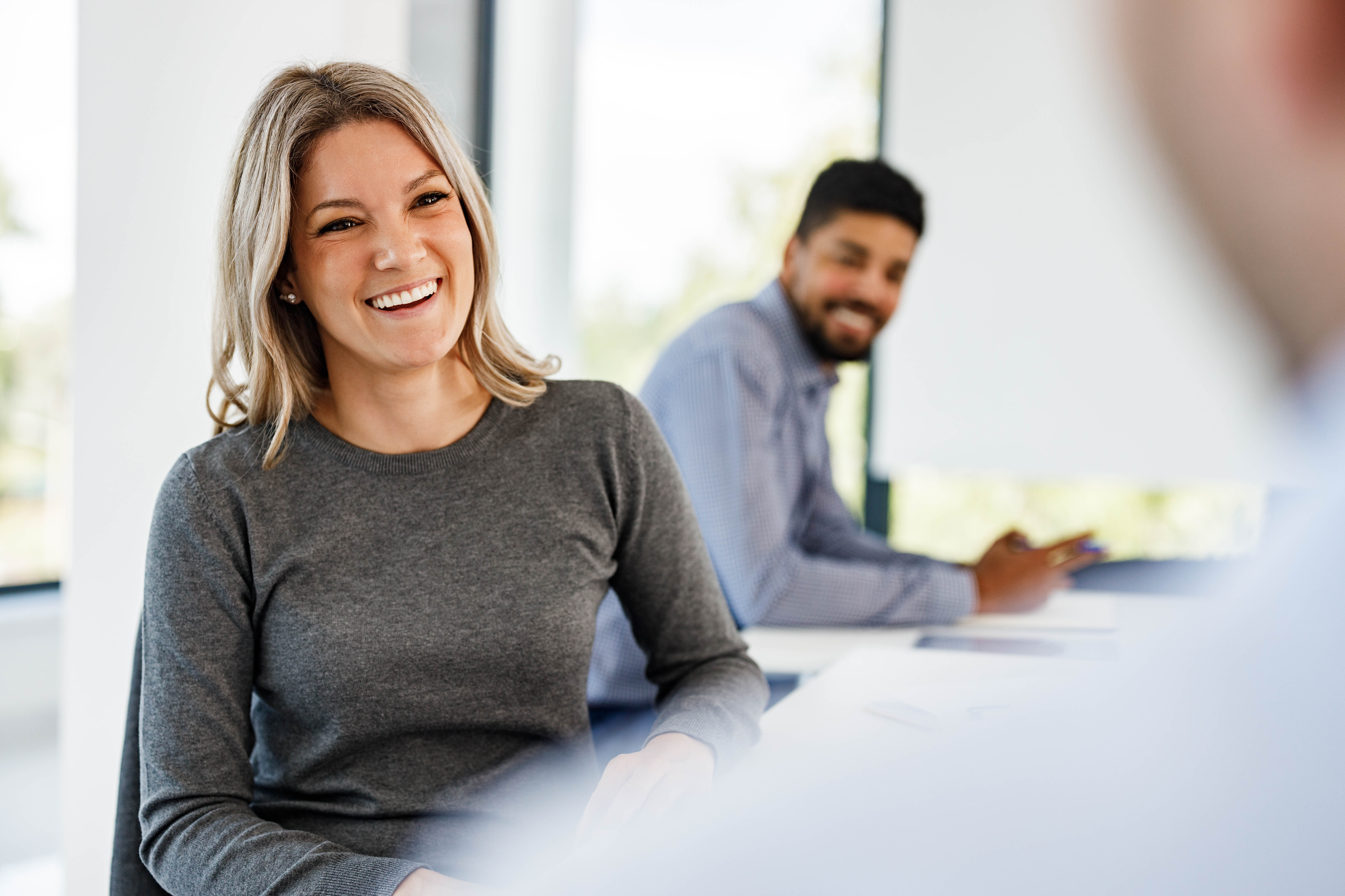 Happy female entrepreneur talking to her colleagues in the office.