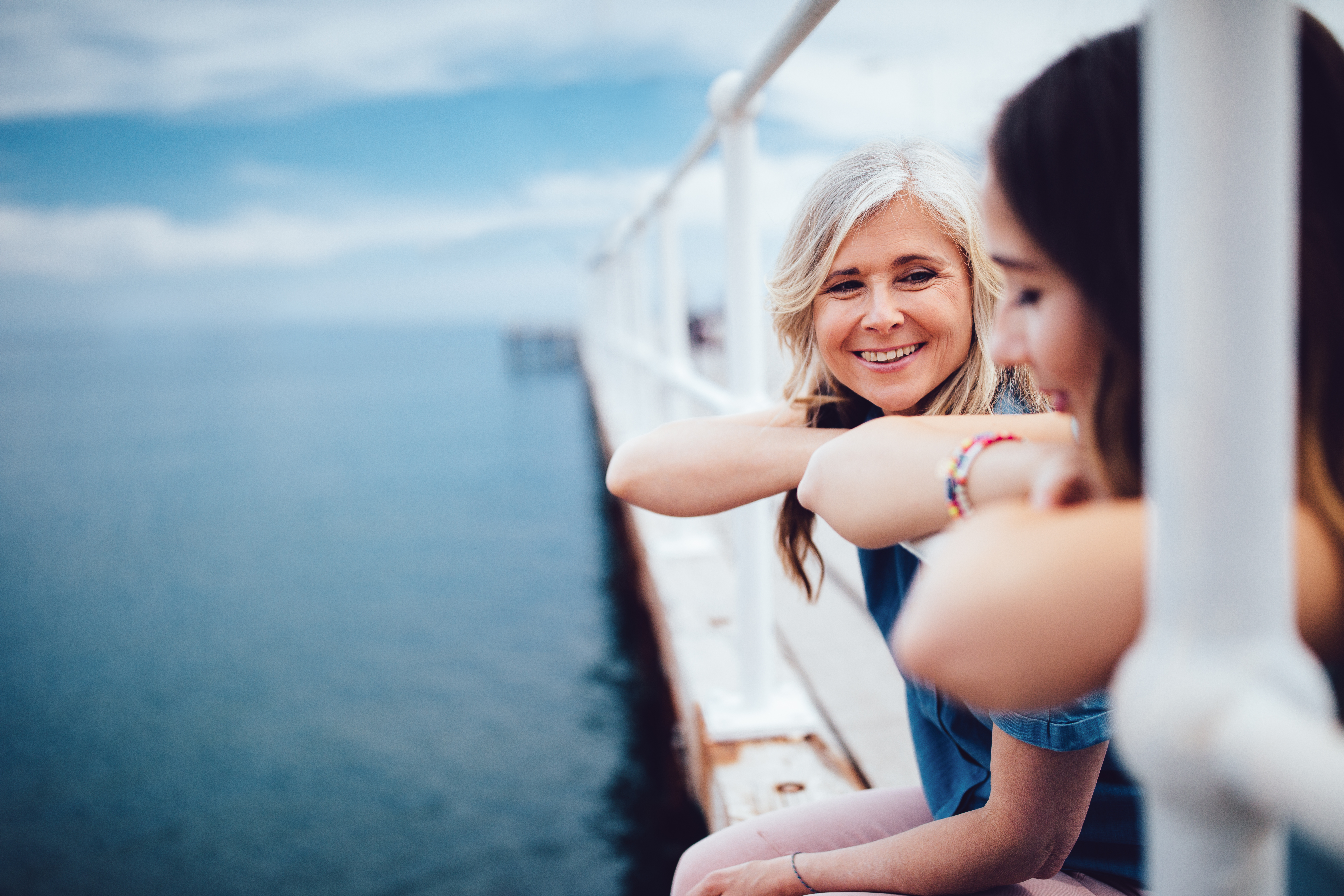 Senior mother and teenage daughter relaxing together on a pier