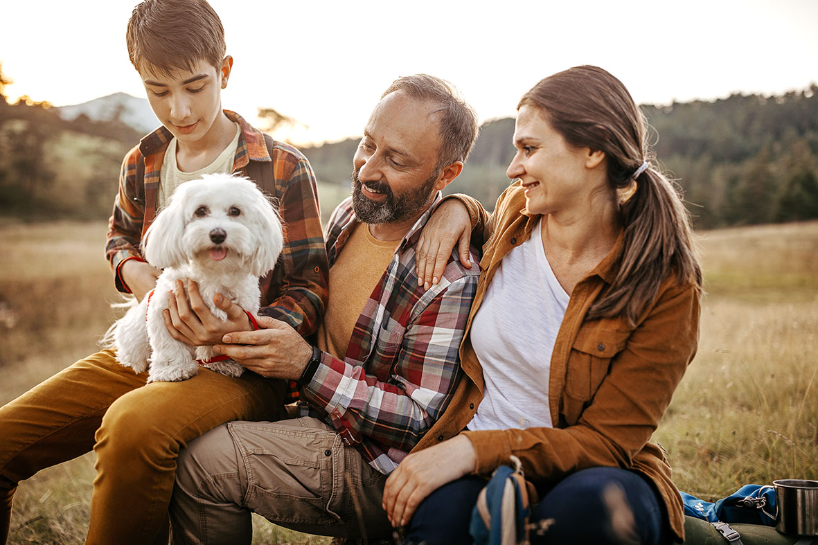 Family with pet dog relaxing while hiking at forest